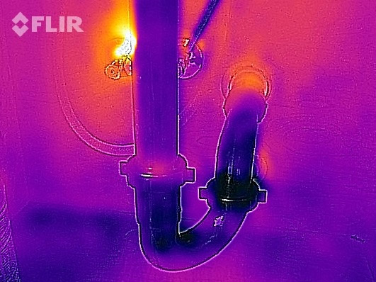 Thermal image of sink pipes in the wall of the bathroom.